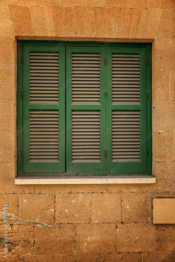 Closed window with wooden green shutters in the house. Close-up.