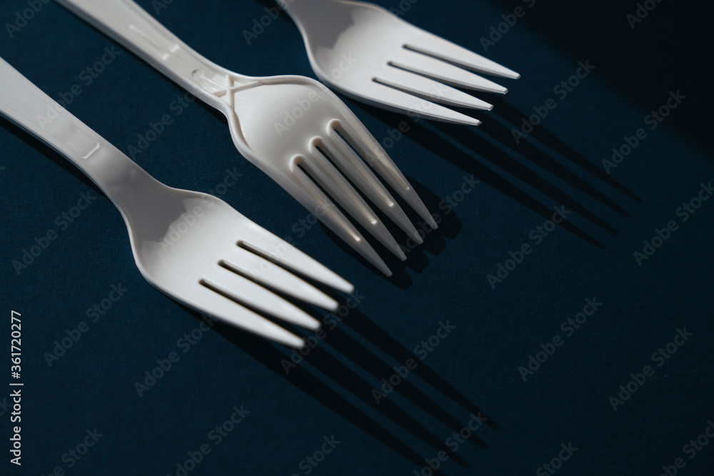 Three white plastic utensil fork laying together.
