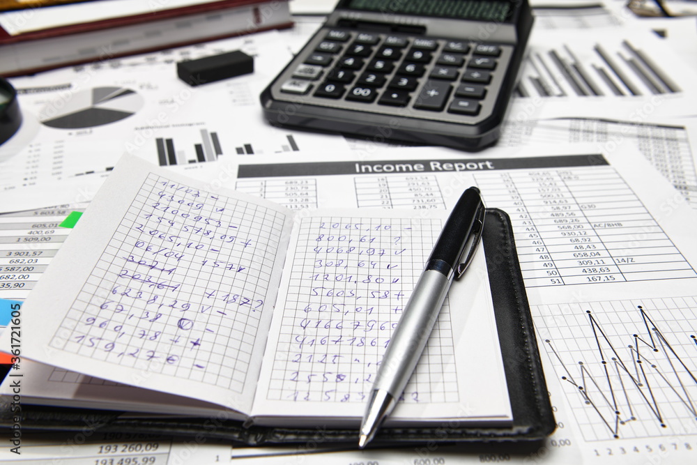 Obraz premium Top view of office employee's desk - work with financial reports, analysis and accounting, tables and graphs, various office items for bookkeeping