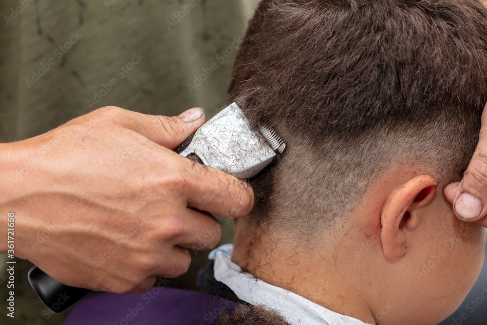 The boy is trimmed with a trimmer The boy is trimmed with a trimmer