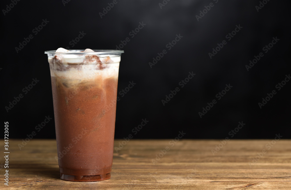 Iced coffee with ice and cream in a plastic glass on a black background with copy space Iced coffee with ice and cream in a plastic glass on a black background with copy space
