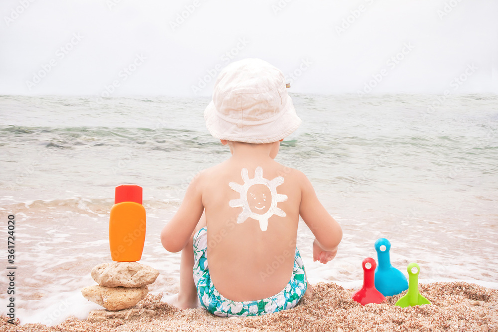 The sun drawing sunscreen on baby (boy)  back.