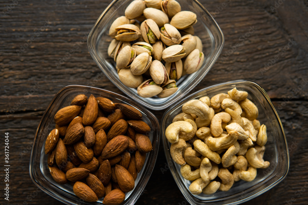 Almond, pistachio and cashew in a small plates which standing on a vintage wooden table. Nuts is a healthy vegetarian protein and nutritious food. Almond, pistachio and cashew in a small plates which standing on a vintage wooden table. Nuts is a healthy vegetarian protein and nutritious food.