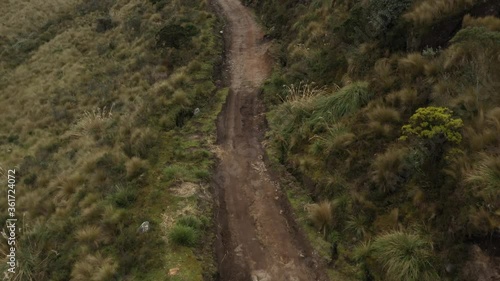 Aerial view, following a dirt road in the andean mountains that looks very rough and hard to drive over
