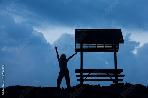 Young woman is relaxing next to a small pavilion..On a dark sky