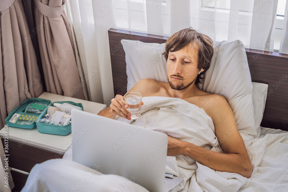 Male patient is sick while lying in his bed and calls an online doctor through a gadget Male patient is sick while lying in his bed and calls an online doctor through a gadget