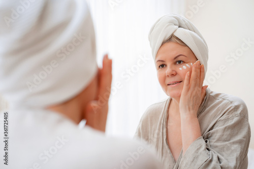 portrait pretty senior woman with hands on her face mirror at home after bathroom Skin care after 50-60 years