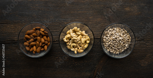 Almond, cashew and sunflower seeds in a small plates which standing on a vintage wooden table. Nuts is a healthy vegetarian protein and nutritious food.