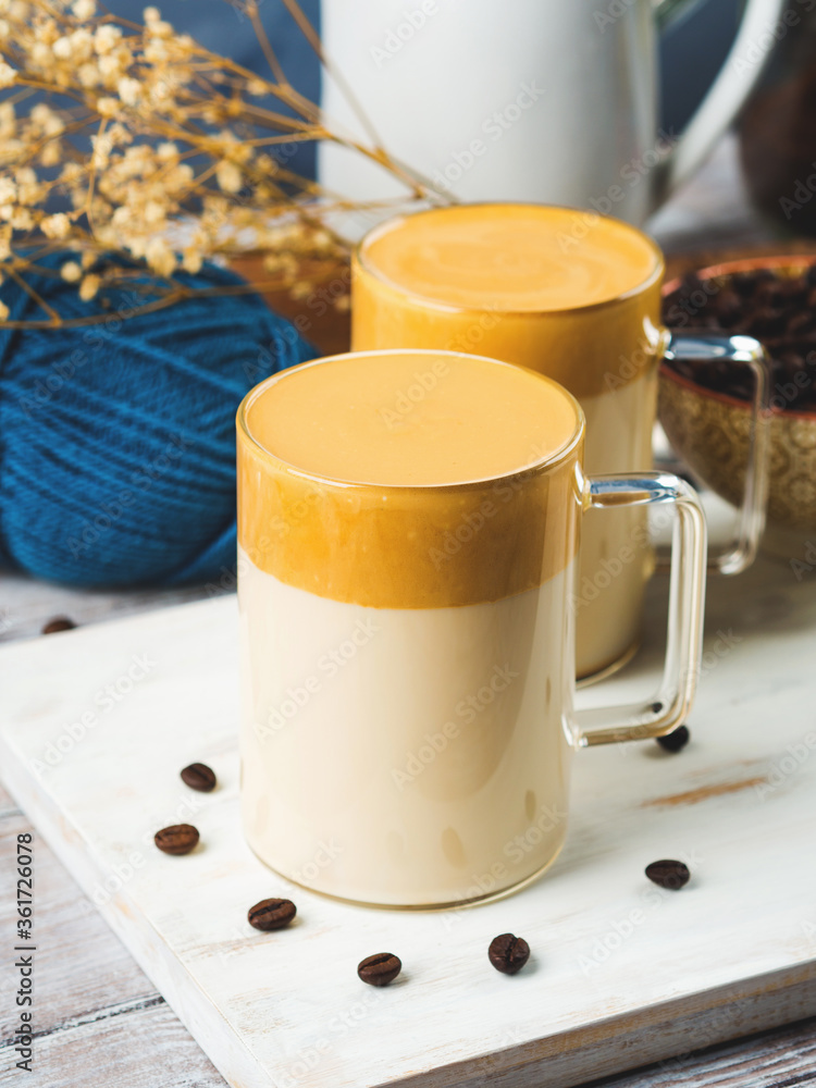 Whipped dalgona coffee drink in transparent mug on white wooden board. Cozy breakfast Whipped dalgona coffee drink in transparent mug on white wooden board. Cozy breakfast