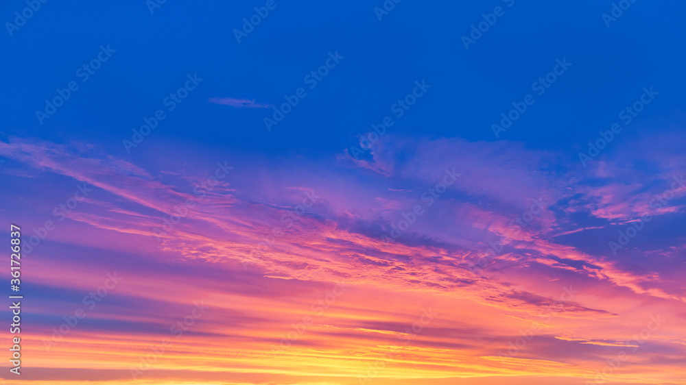 Bright blue sky with red-yellow clouds. Summer sunset.