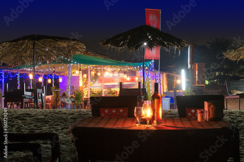 Fototapeta Naklejka Na Ścianę i Meble -  Beach party at night in beach cafe with bottle of rose wine and glasses on the table , GOA, India..