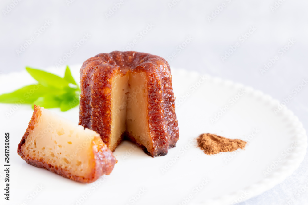 Canele, French confectionery, with a cut loaf, on a white and grey background Canele, French confectionery, with a cut loaf, on a white and grey background
