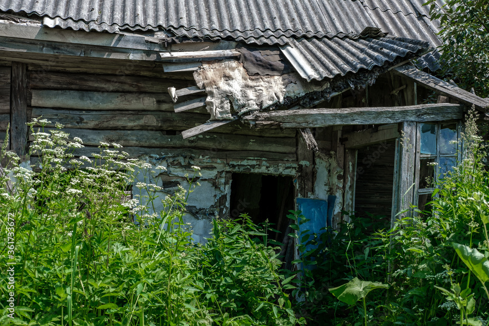 Entrance to an old village house with a collapsed roof and walls, among tall grass. Entrance to an old village house with a collapsed roof and walls, among tall grass.