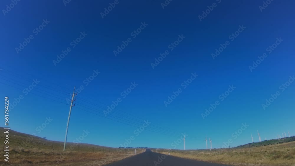 Driver’s view of the Capital Wind Farm showing large wind turbines located along a countryside road near Lake George in New South Wales, Australia Driver’s view of the Capital Wind Farm showing large wind turbines located along a countryside road near Lake George in New South Wales, Australia