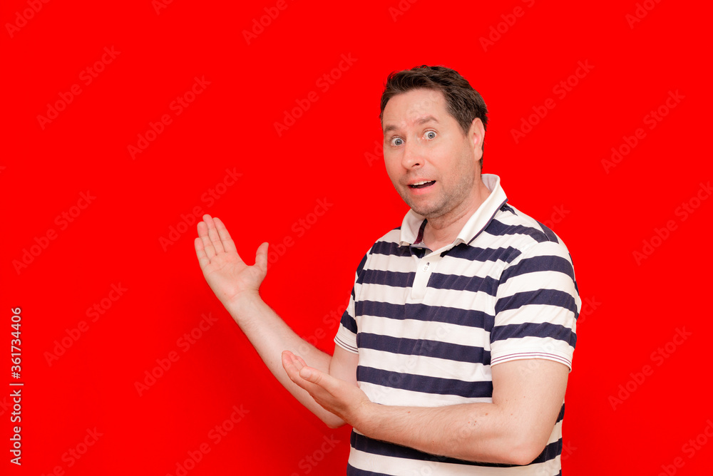 Cheerful man wearing striped t shirt pointing at palm, showing product Cheerful man wearing striped t shirt pointing at palm, showing product
