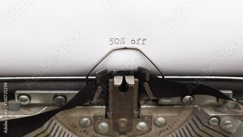 Typing a text of special offer fifty percent or 50% off on a vintage typewriter close-up. concept of wholesale discount on christmas sales
