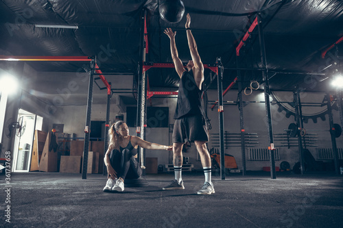 Beautiful young sporty couple workout in gym together. Caucasian man training with female trainer. Concept of sport, activity, healthy lifestyle, strength and power. Working out with ball. © master1305