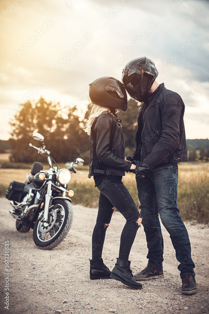 Road trip. A couple all in black, near the motorcycle at the sunset Road trip. A couple all in black, near the motorcycle at the sunset