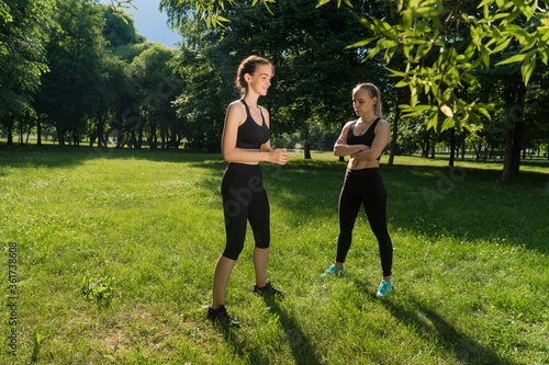 Fototapeta Naklejka Na Ścianę i Meble -  female fitness coach is engaged with a client outdoors. The concept of social distance during weight training in the park