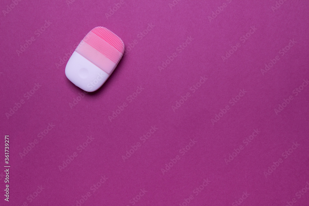 pink electric face massager on purple background, top view with copy space pink electric face massager on purple background, top view with copy space
