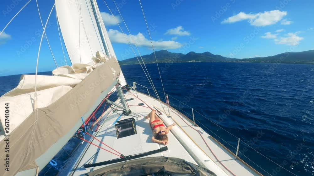 Woman sunbathes on yacht while it sails on water. Woman sunbathes on yacht while it sails on water.