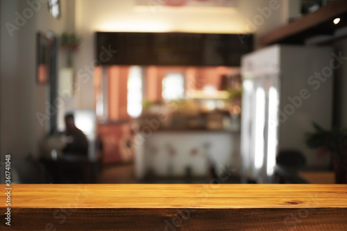 Empty wooden desk space and blurry background of cafe or Restaurant for product display montage. © qOppi