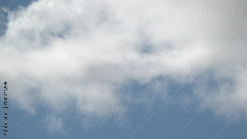 A time lapse of thick and billowing white clouds pass across a bright blue summer sky. A time lapse of thick and billowing white clouds pass across a bright blue summer sky.