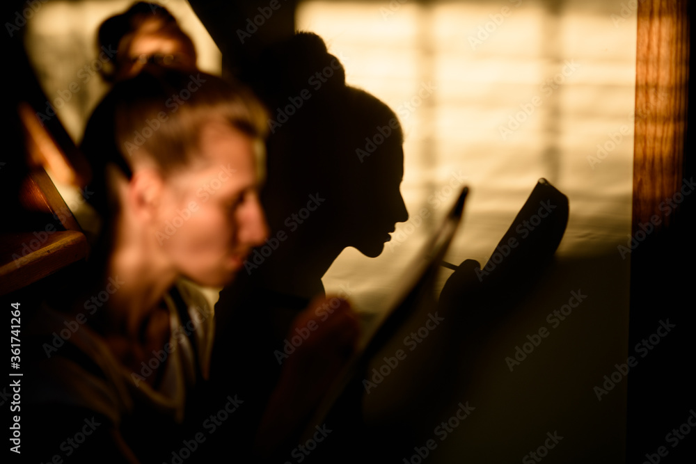 young woman sits and and the shadow from her face falls on the wall. young woman sits and and the shadow from her face falls on the wall.