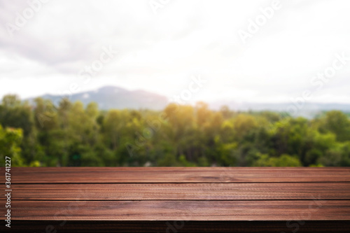 Empty wooden desk space and blurry background of mountain or hill.