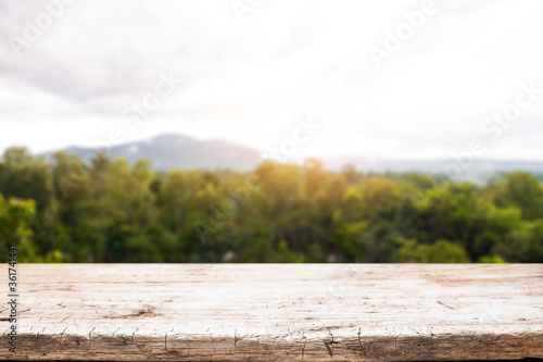 Empty wooden desk space and blurry background of mountain or hill.