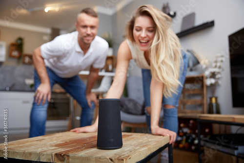 Smiling Woman With Boyfriend Looking At Smart Speaker photo