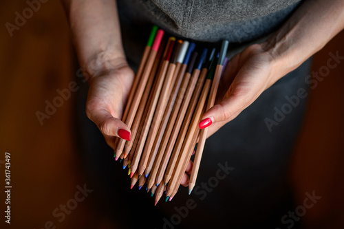 Closeup of many colored pencils in woman's hands.