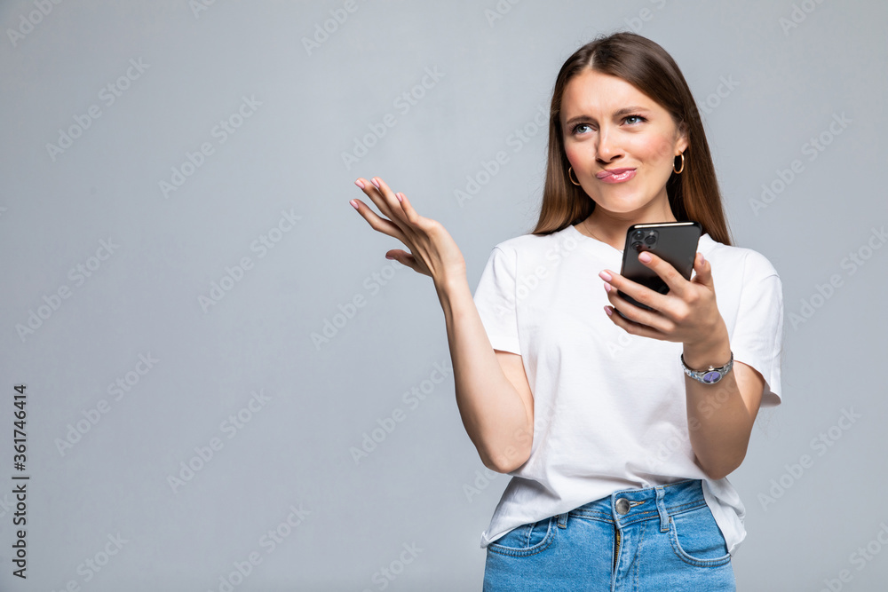 Disappointed confused woman using smartphone isolated on a white background Disappointed confused woman using smartphone isolated on a white background
