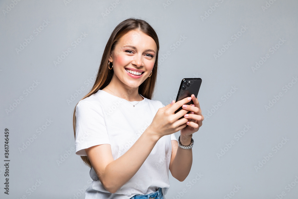 Young Woman smiling and texting on her mobile phone, isolated over white background. Young Woman smiling and texting on her mobile phone, isolated over white background.