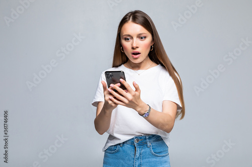 Exciting woman reading text message on the phone isolated on gray background