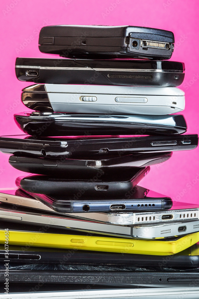 outdated and modern models of smartphones and mobile phones. dirty, broken and old smartphones on a pink background outdated and modern models of smartphones and mobile phones. dirty, broken and old smartphones on a pink background