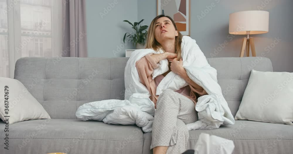 Sick Caucasian bad-looking young woman sitting on couch at home in blanket and measuring temperature. Ill girl with flu or coronavirus having fever and feeling bad Female on sofa with corona sympthoms Sick Caucasian bad-looking young woman sitting on couch at home in blanket and measuring temperature. Ill girl with flu or coronavirus having fever and feeling bad Female on sofa with corona sympthoms