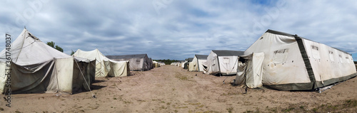 old soldiers canvas tents torn in the wind in the field. Tent city on military exercises photo