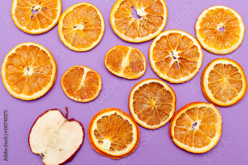 One slice apple stand out between many slices of orange isolated on purple background