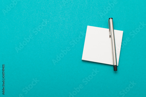 Notebook and pen isolated on aquamarine background 