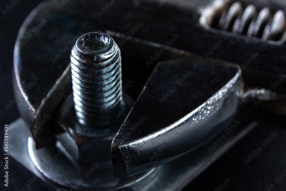 Adjustable wrench tightens the nut on the bolt, close-up Adjustable wrench tightens the nut on the bolt, close-up