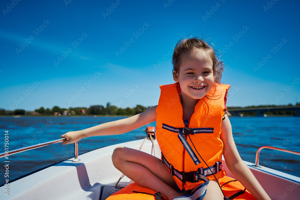 little girl in a swimming vest sits in a motorboat