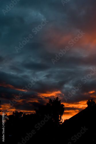 Silhouette of street of houses exterior in sunset with dark sky behind buildings