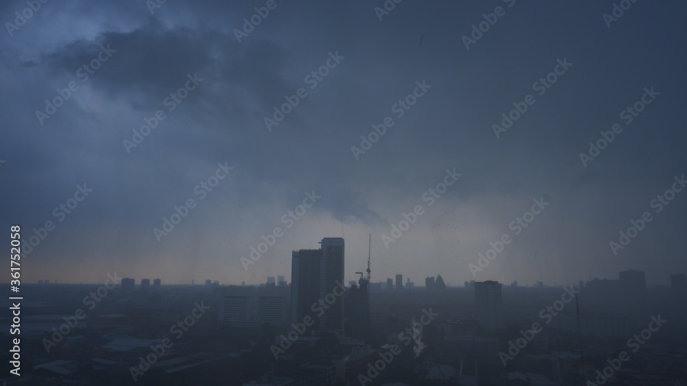 Fototapeta premium Widok z lotu ptaka, tropikalna burza z ulewnym deszczem, silne wiatry chmury burzowe szybko przesuwające się nad panoramą miasta.