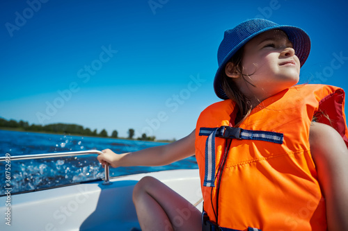 Tela little girl in a swimming vest sits in a motorboat