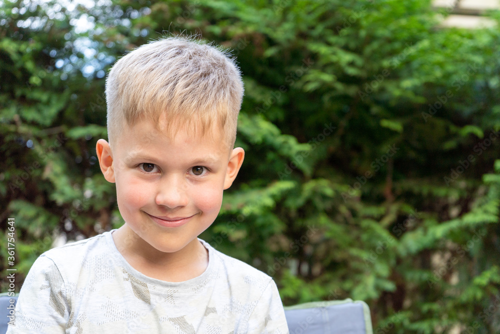 Cute boy portrait smiling and looking into Camera. Happy handsome child outdoors on a sunny day with toothy smile. Cute boy portrait smiling and looking into Camera. Happy handsome child outdoors on a sunny day with toothy smile.