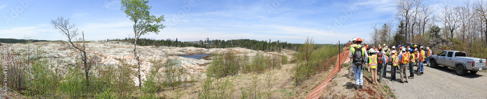 SUDBURY, ONTARIO, CANADA - MAY 21 2009: Group of workers and geologists in hardhats and high-visibility vests standing on road. SUDBURY, ONTARIO, CANADA - MAY 21 2009: Group of workers and geologists in hardhats and high-visibility vests standing on road.