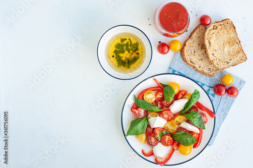 A light summer dinner. Red and yellow vegetable salad, tomato juice, basil sauce and toast. Copy Space.