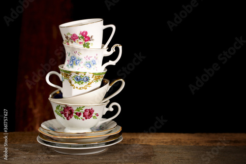 Konstfotografi Stack of various English vintage porcelain teacups with floral decoration on dark background