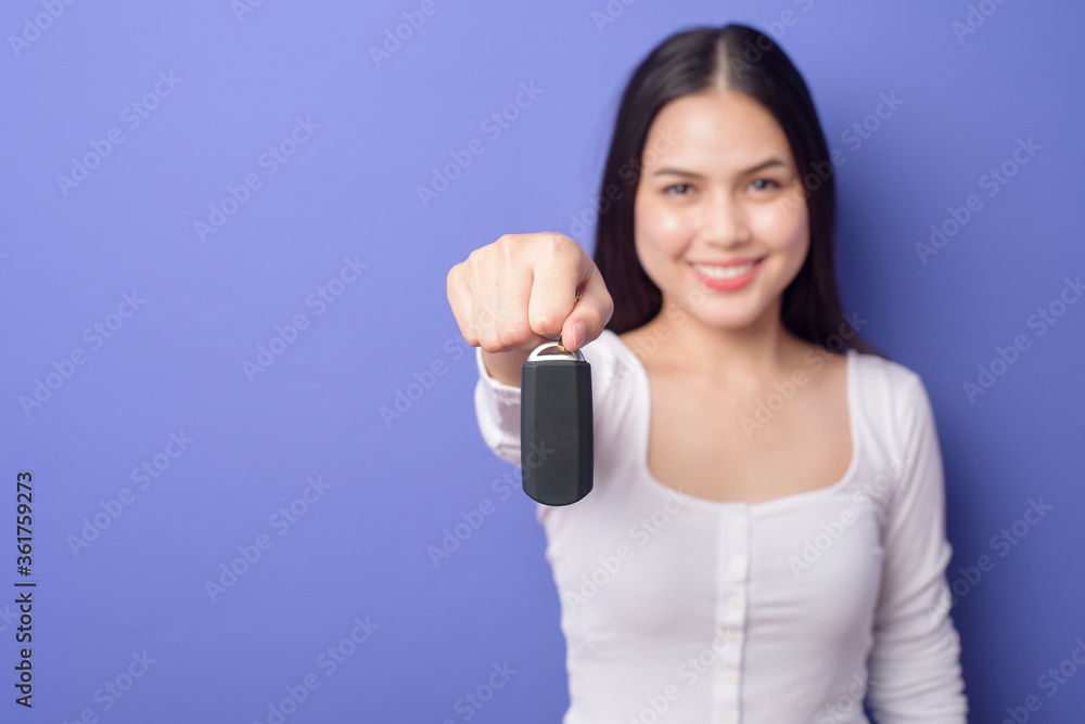 Young beautiful smiling woman is holding car key over isolated purple background studio Young beautiful smiling woman is holding car key over isolated purple background studio